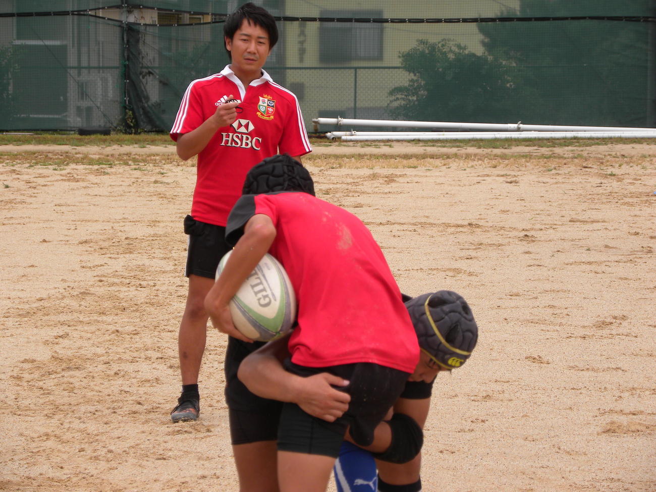 森祥太郎監督（奥）が見守る中でタックル練習する膳所の選手たち（撮影・松本航）