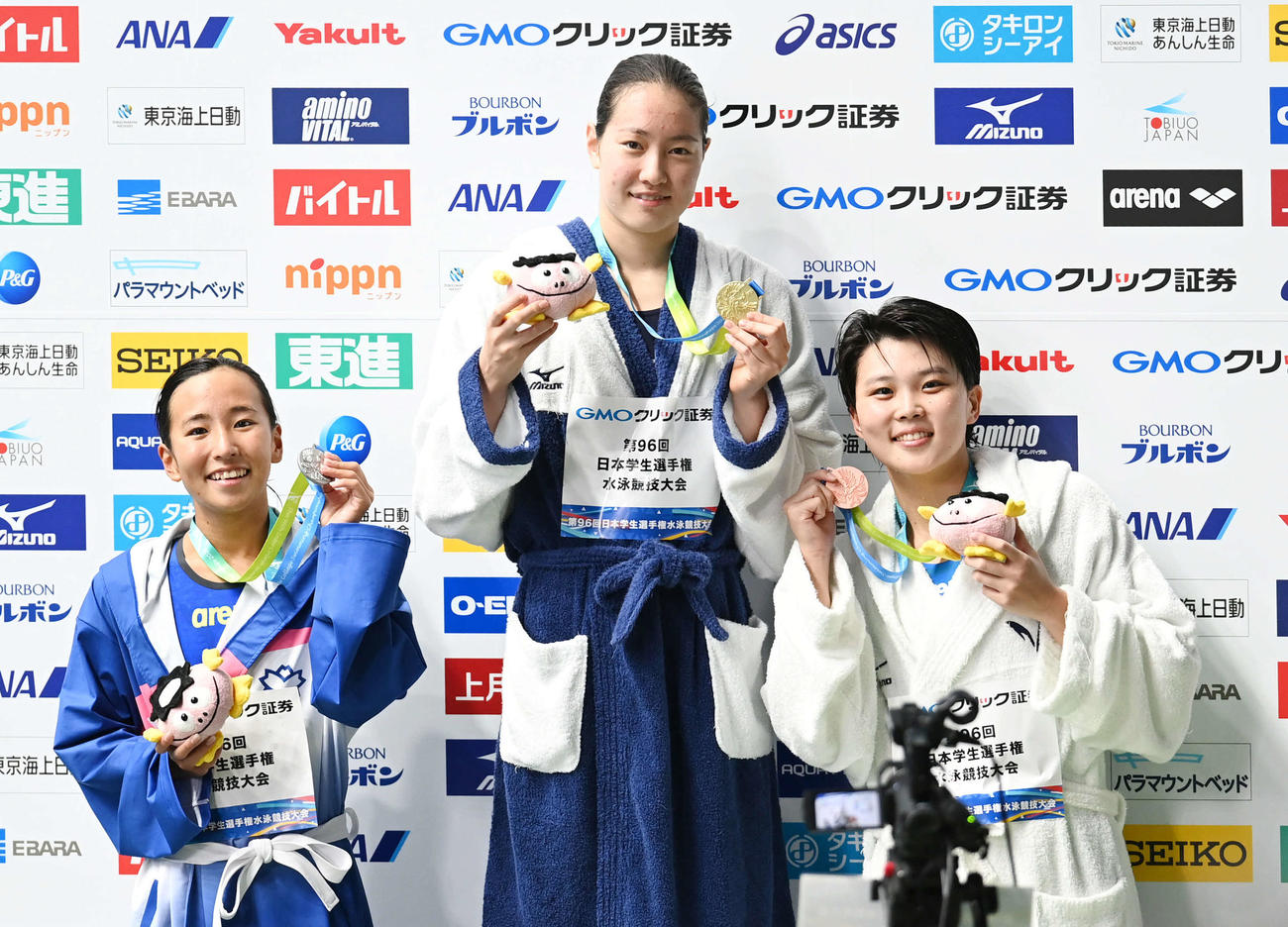 女子100メートル背泳ぎ決勝　優勝した東洋大・酒井（中央）は2位の日体大・竹内（左）と3位の明大・湯原と笑顔を見せる（撮影・山崎安昭）