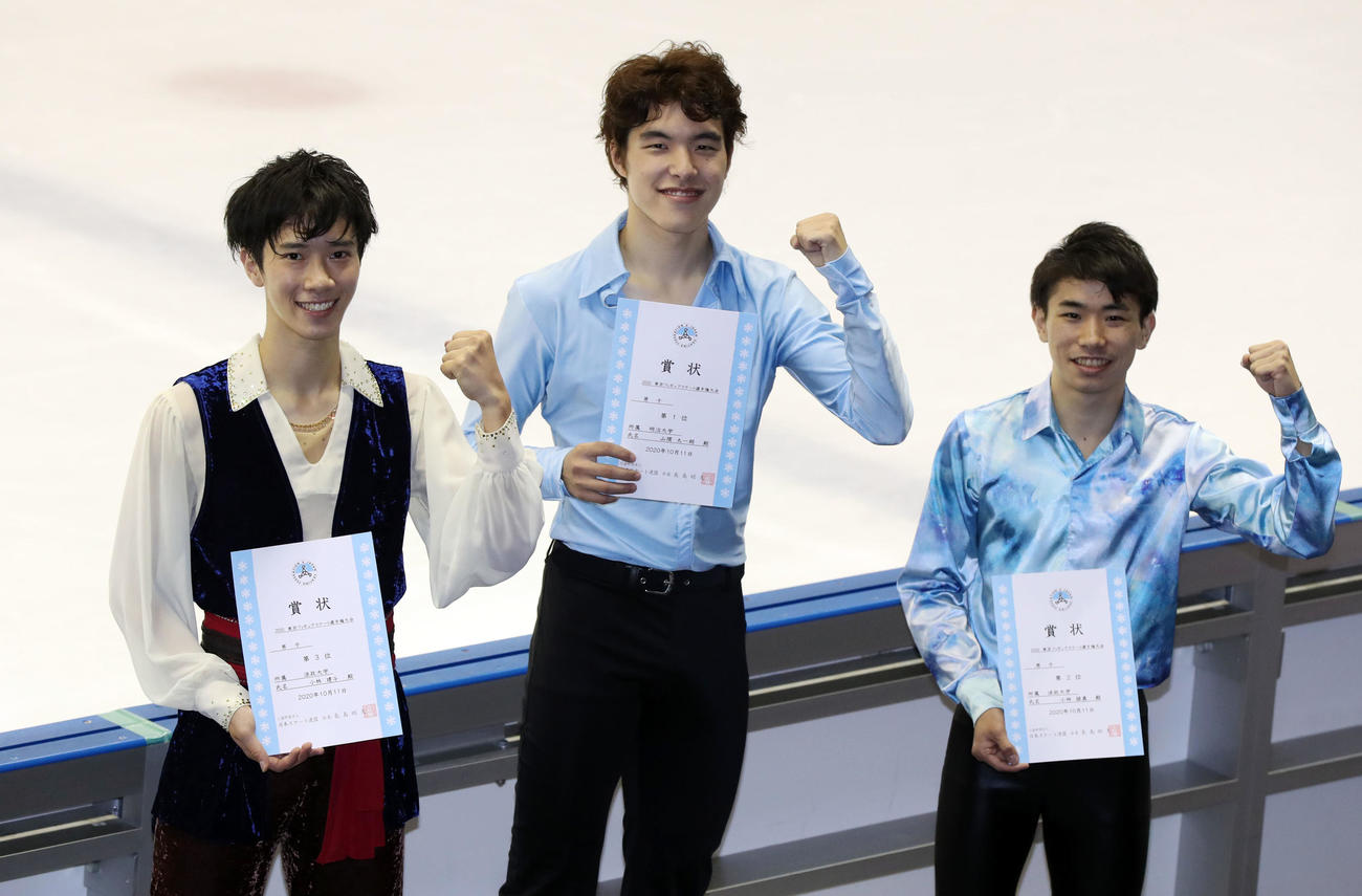 男子フリーの表彰式でガッツポーズを見せる優勝した山隈（中央）。左は2位の小林建、右は3位の小林諒（撮影・狩俣裕三）