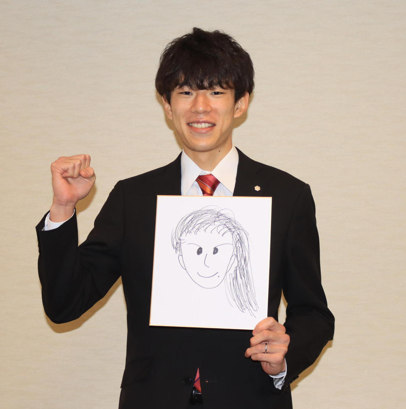 夫人の似顔絵を持ち、ガッツポーズする雪印メグミルクの佐藤慧（撮影・保坂果那）