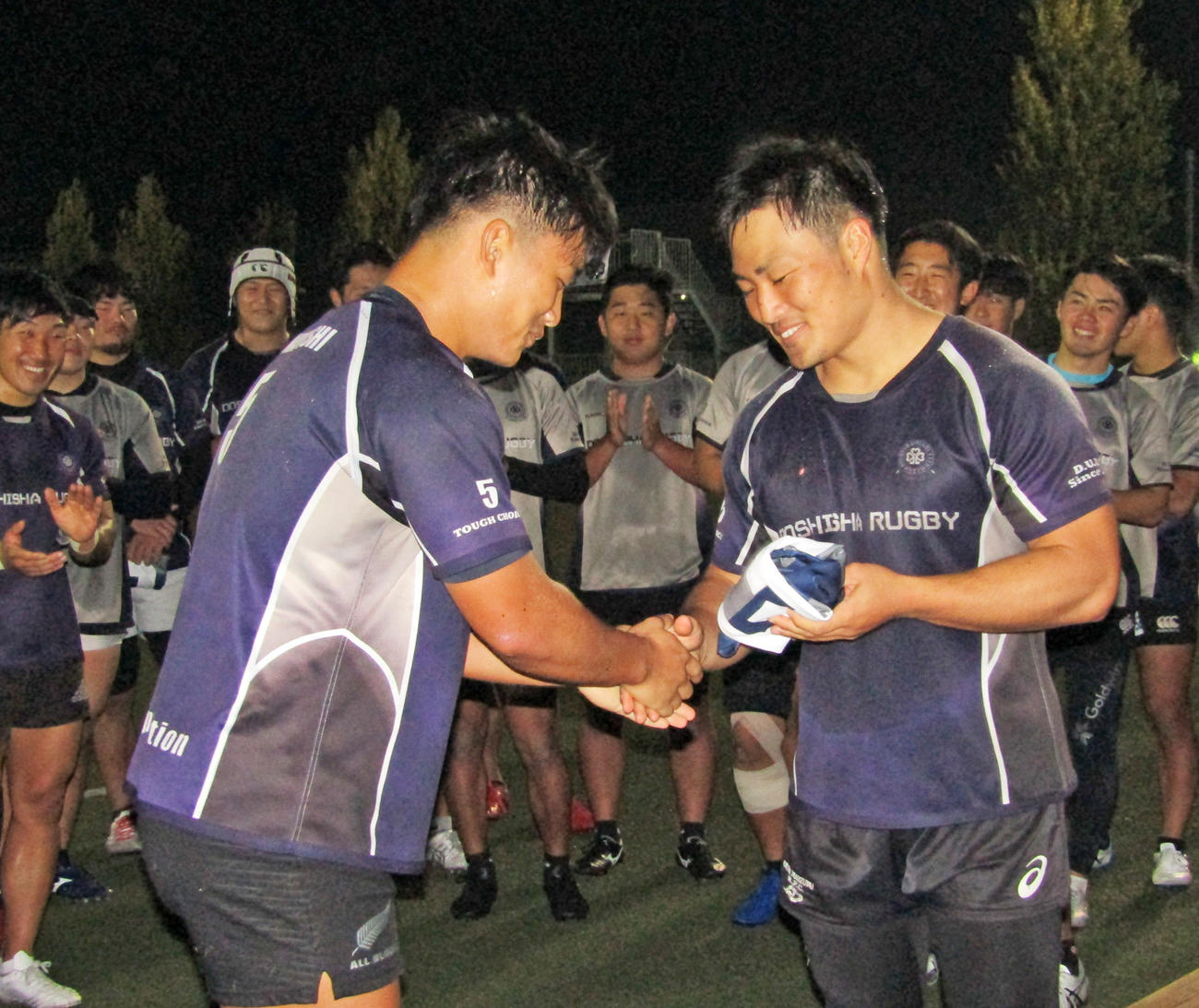 メンバーにジャージーを手渡し、握手をする同大・中尾主将（右）（撮影・佐藤あすみ）