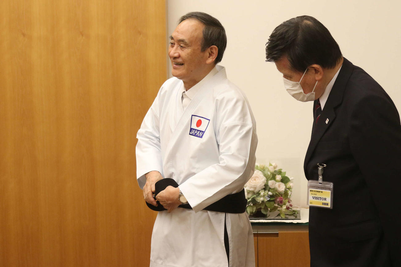 記念の道着に袖を通し、笑顔を浮かべて黒帯を締める菅首相＝（公財）全日本空手道連盟提供