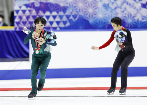 表彰式を終え、トロフィーを落としそうになる優勝した鍵山優真。右は2位の友野一希（代表撮影）