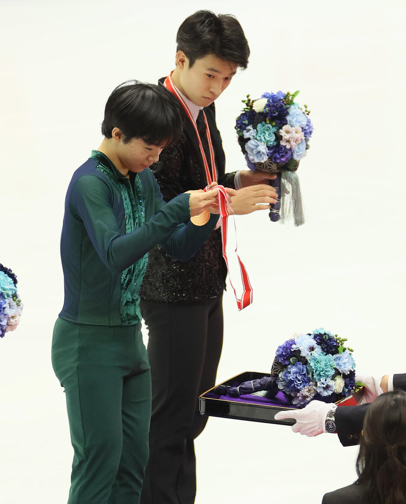 表彰式でメダルを見つめる、優勝した鍵山優真（手前）。奥は3位の本田ルーカス剛史（代表撮影）