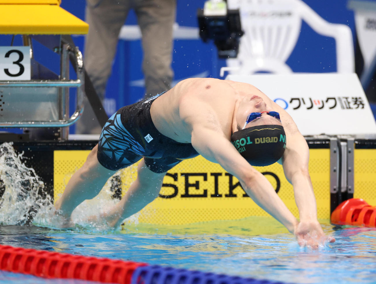 男子200メートル背泳ぎ決勝で勢いよくスタートする入江（撮影・河野匠）