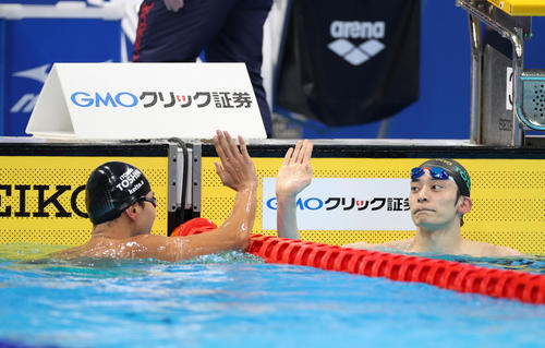 男子200メートル背泳ぎで優勝した入江（右）は2位の砂間とハイタッチを交わす（撮影・河野匠）