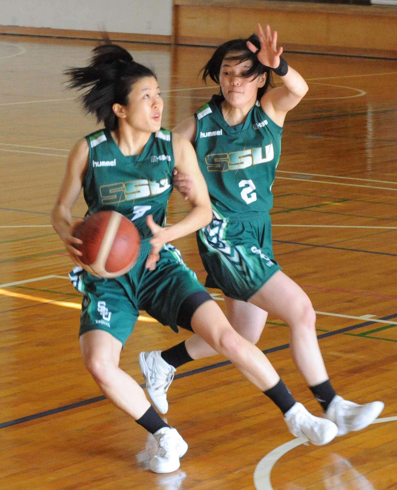 シュートを狙う静岡産大女子の浜本主将（左）