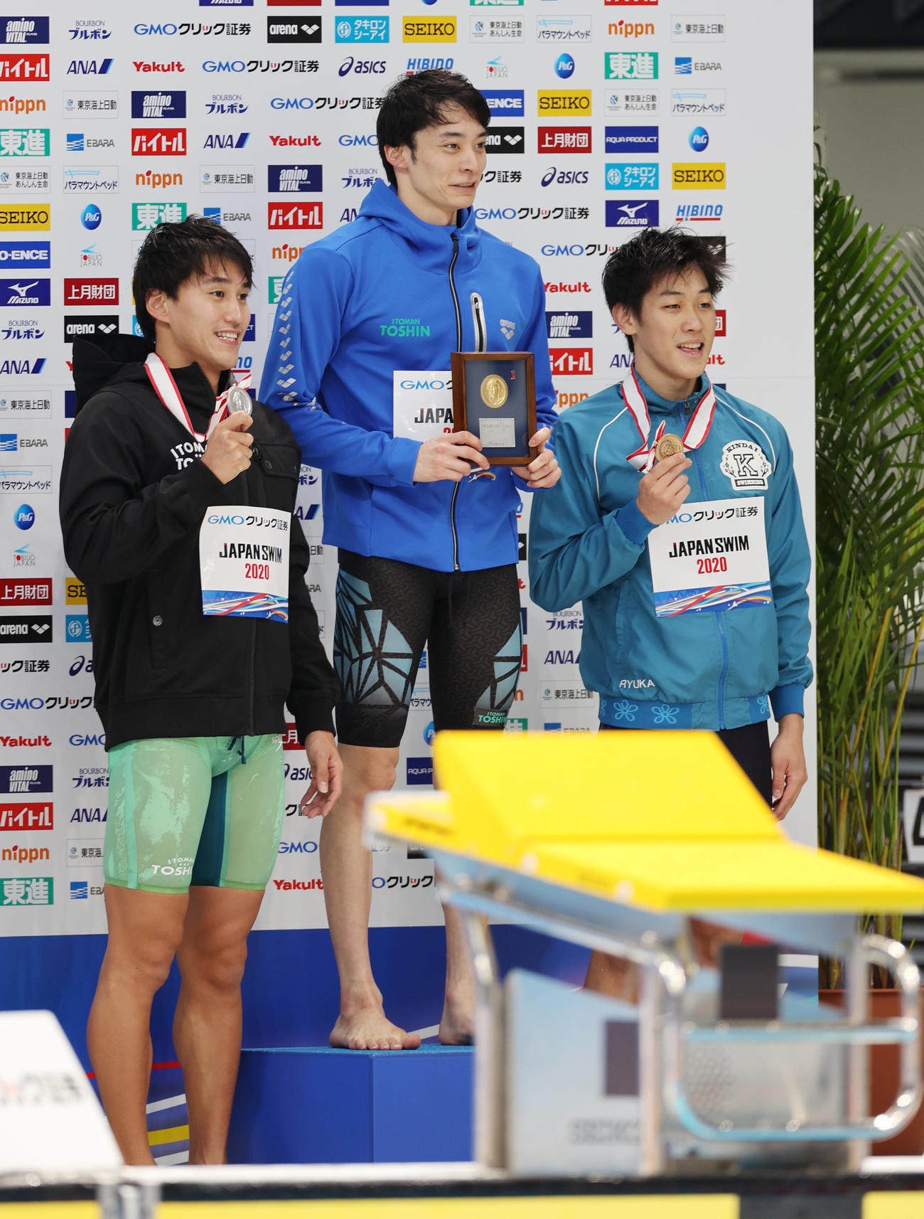 男子200メートル背泳ぎで優勝し記念撮影に納まる入江（中央）。左は2位の砂間、右は3位の井野（撮影・河野匠）