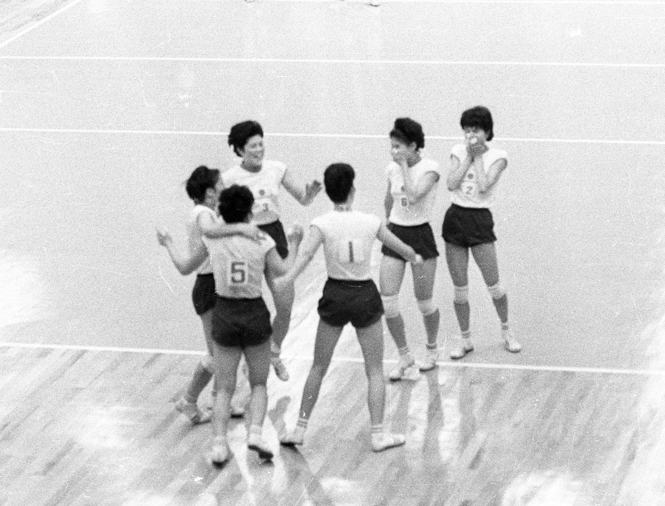 64年東京五輪で宿敵ソ連を破って金メダルが決まり、キャプテン河西昌枝（1番）のもとへ駆け寄る選手たち。左上が谷田（井戸川）絹子さん（1964年10月23日撮影）