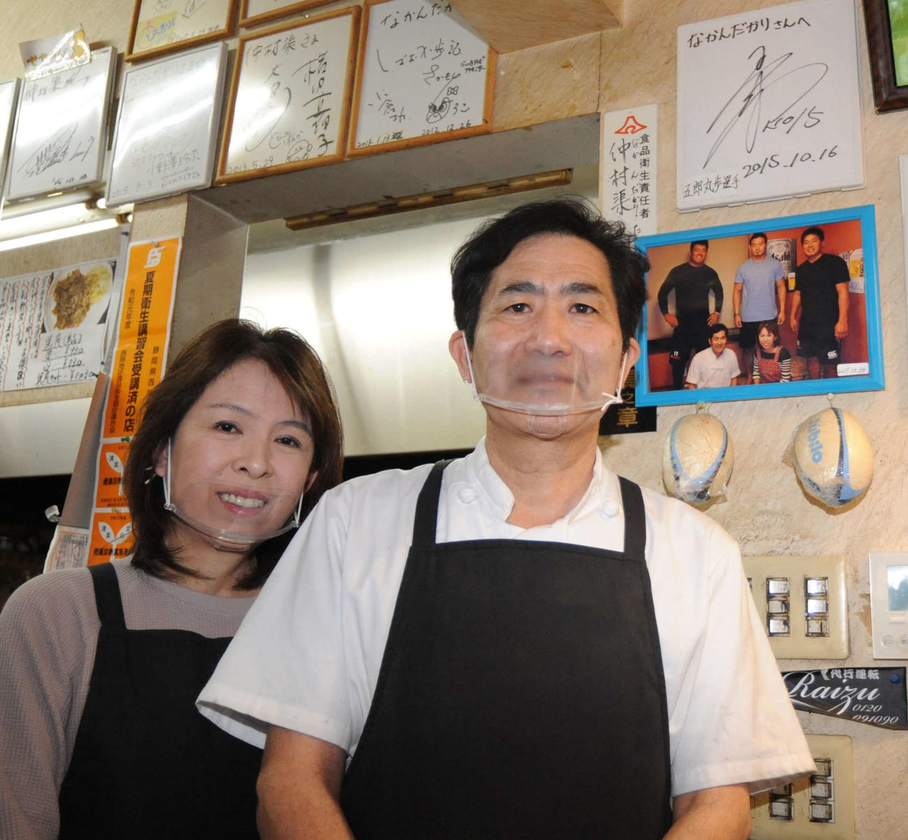五郎丸のサイン（右上）と写真に納まる「仲村渠」の店主夫妻