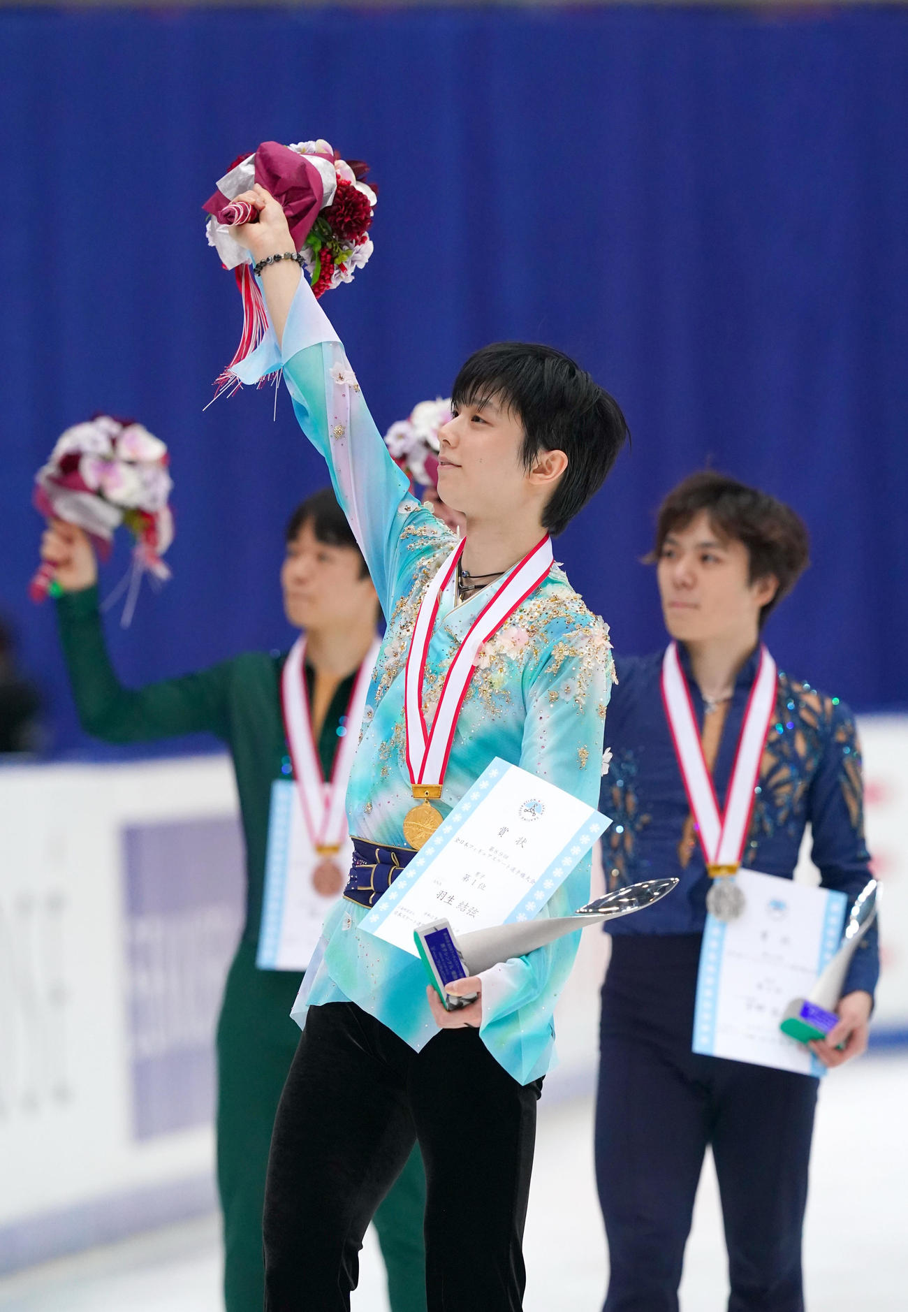 観客に手を振る優勝した羽生。右は2位の宇野、左は3位の鍵山（代表撮影）