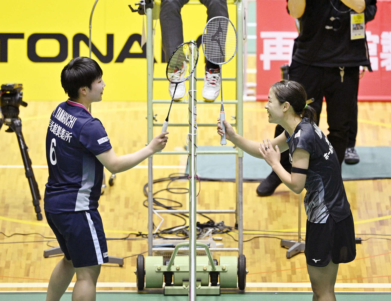 女子シングルスで優勝し、山口（左）とネット越しにラケットでタッチする奥原（代表撮影）
