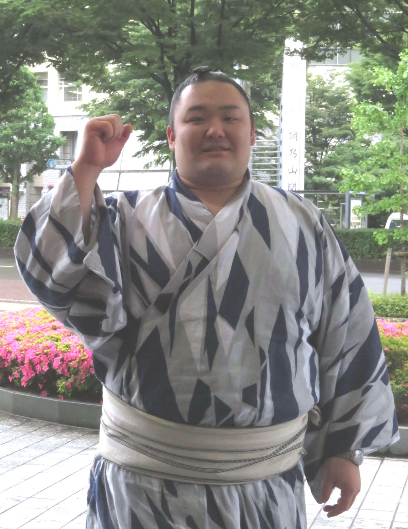 富山市役所に掲げられた「祝初優勝」と書かれた懸垂幕を背に、ガッツポーズをつくる朝乃山（2019年5月31日撮影）