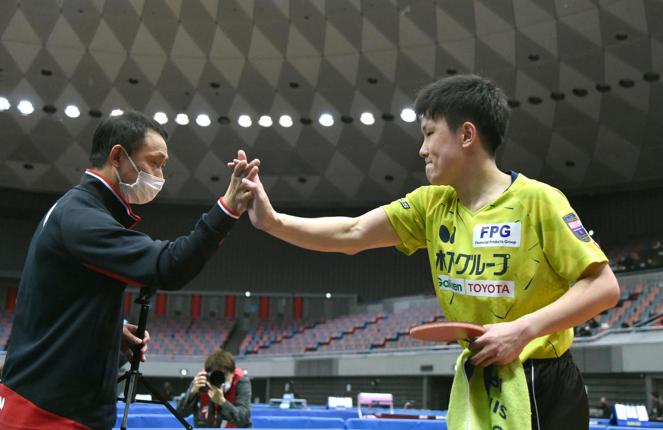 全日本卓球選手権男子シングルス6回戦　フルセットの死闘を制し、父の張本宇コーチ（左）と力強くハイタッチする張本智和（撮影・岩下翔太）