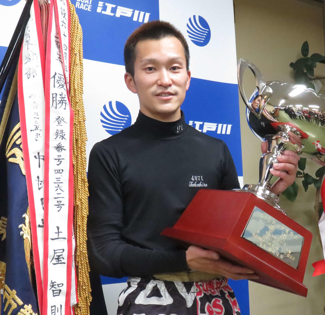 優勝カップを手にして笑顔を見せる西山貴浩