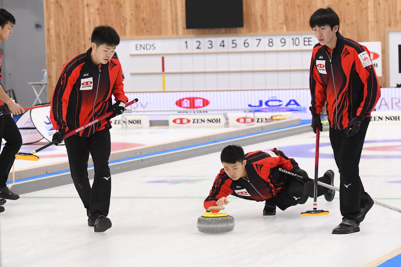 ストーンを投じる常呂ジュニアの前田海（中央）。左はセカンド前田紀、右はリード中原（c）JCA IDE