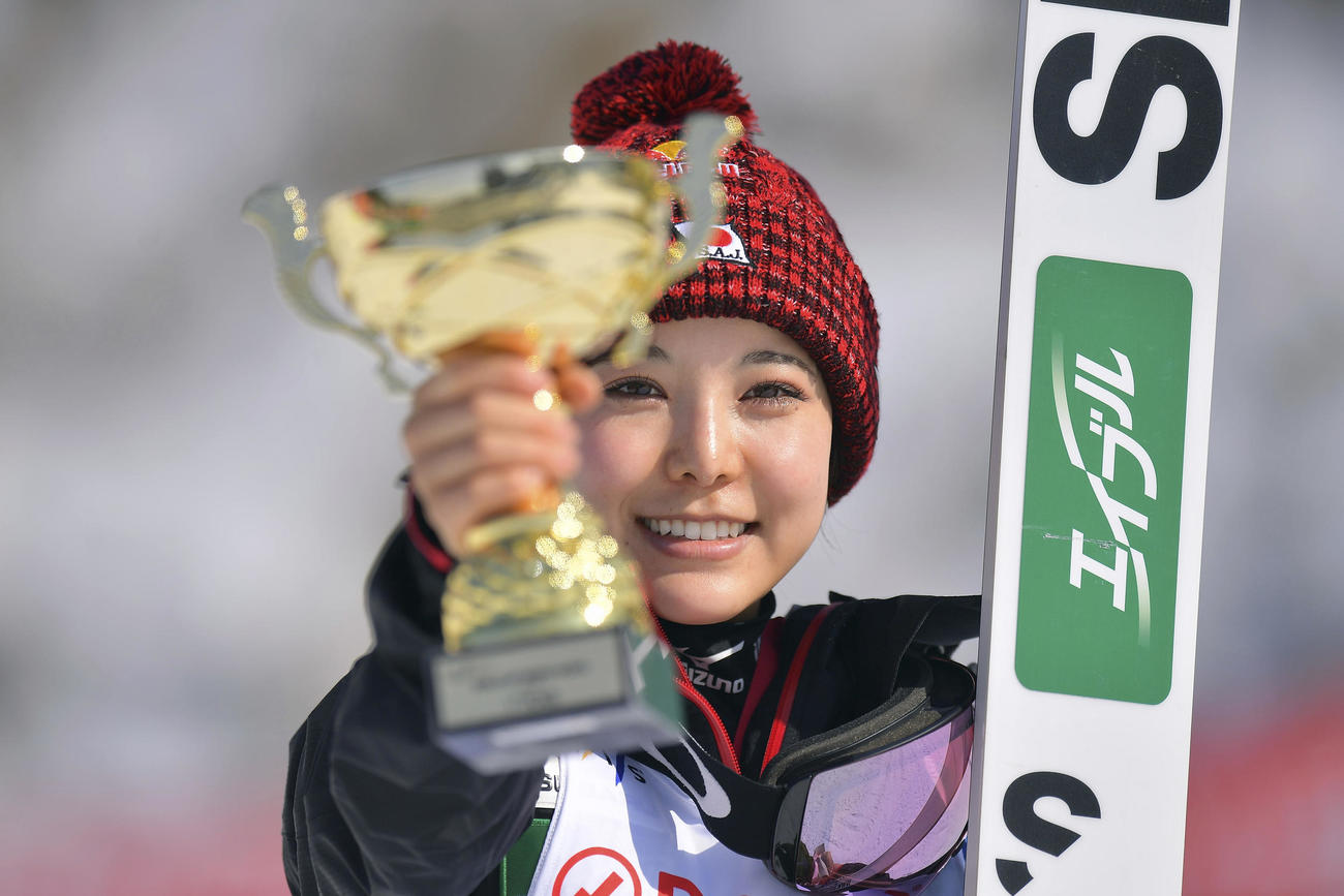 優勝カップを突き出し笑顔を見せる高梨（AP）