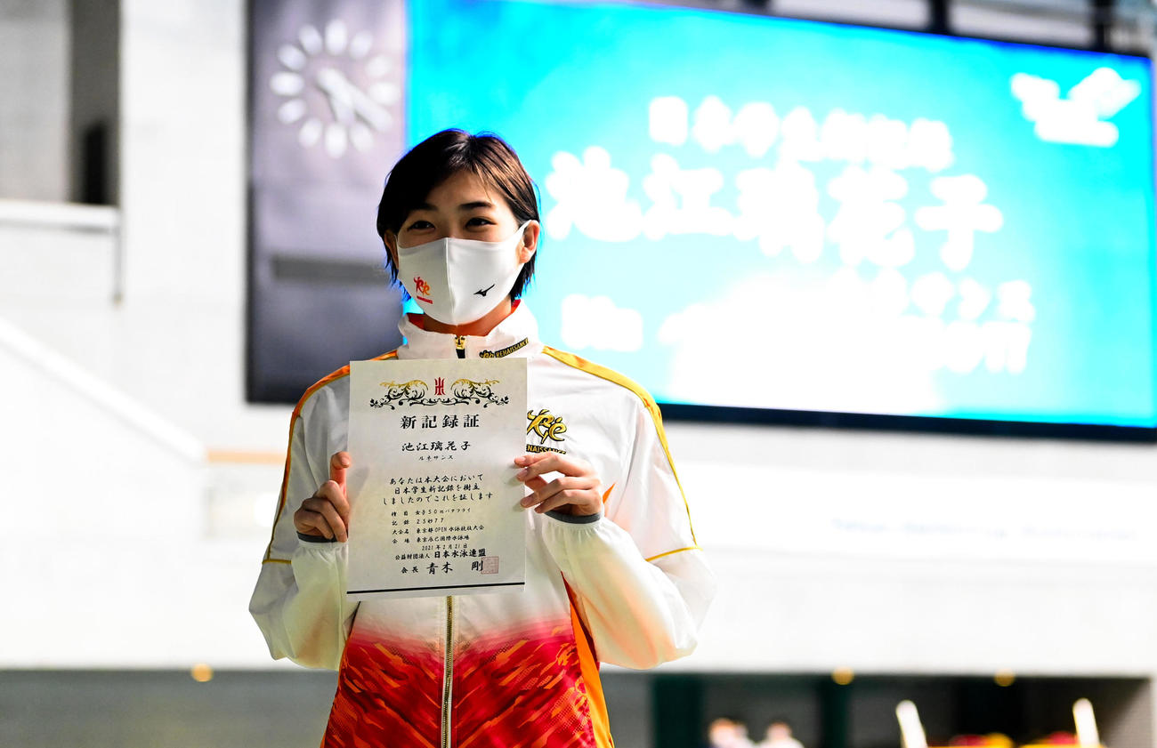 女子50メートルバタフライで日本学生新記録を樹立し、表彰状を手に写真に納まる池江（代表撮影）
