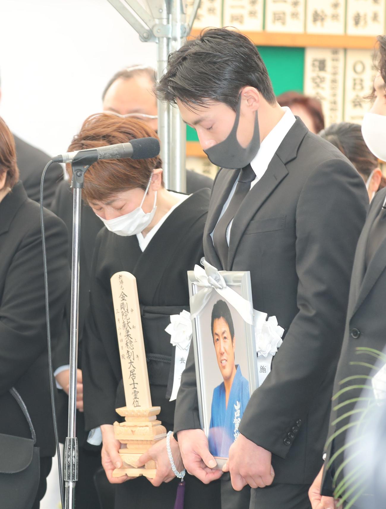 古賀稔彦さんの遺影を手にあいさつする長男・颯人さん（右）と妻・早苗さん（代表撮影）