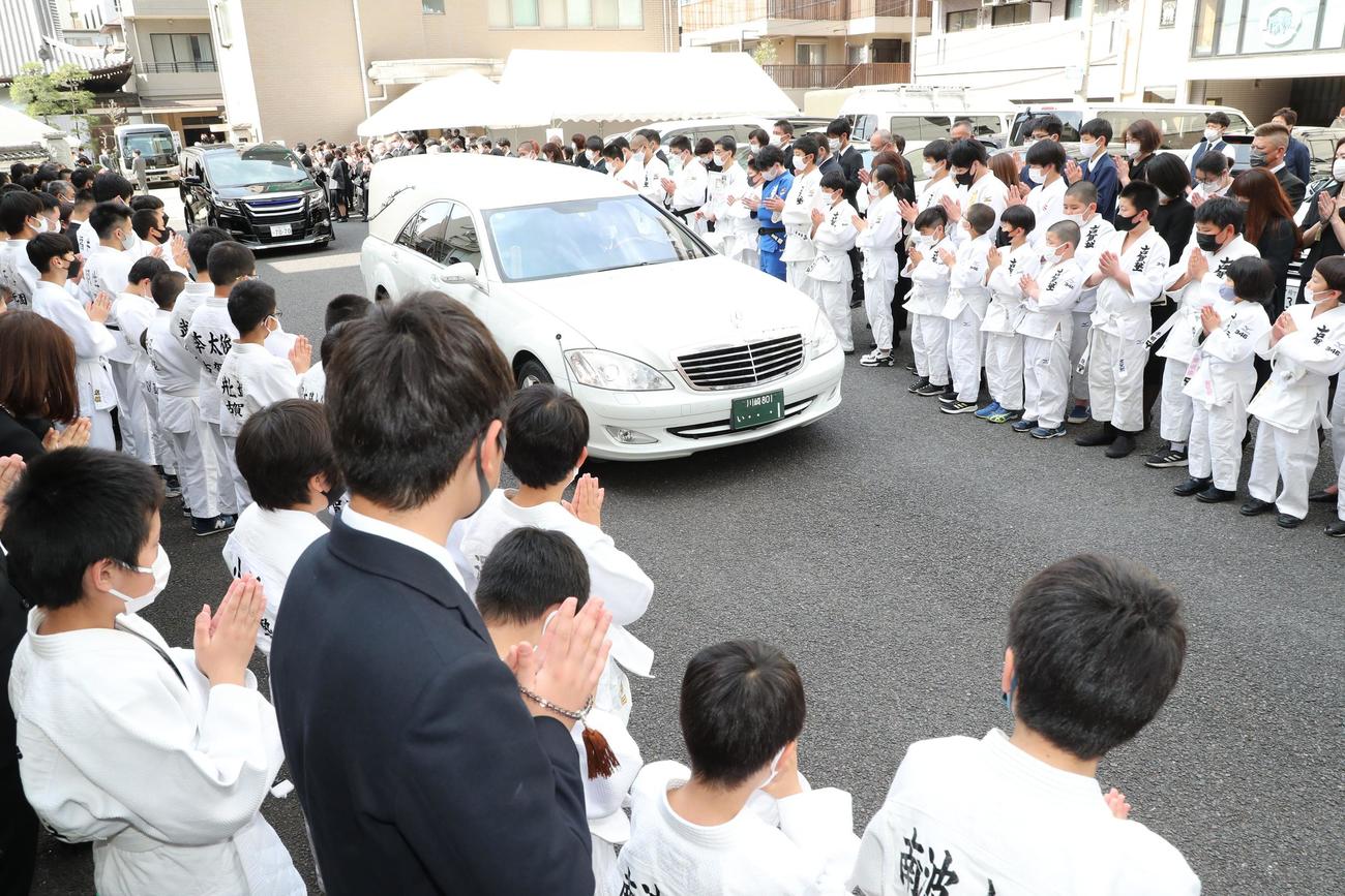 柔道着を着た古賀塾の子どもたちに見送られ斎場を出る古賀稔彦さんの棺を乗せた霊柩車（代表撮影）