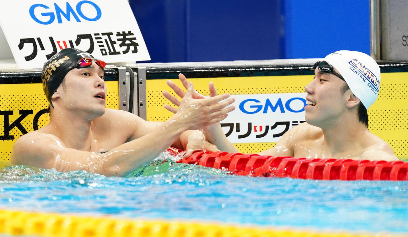 男子100メートル自由形で優勝し2位の松元（右）と握手をする中村（撮影・菅敏）