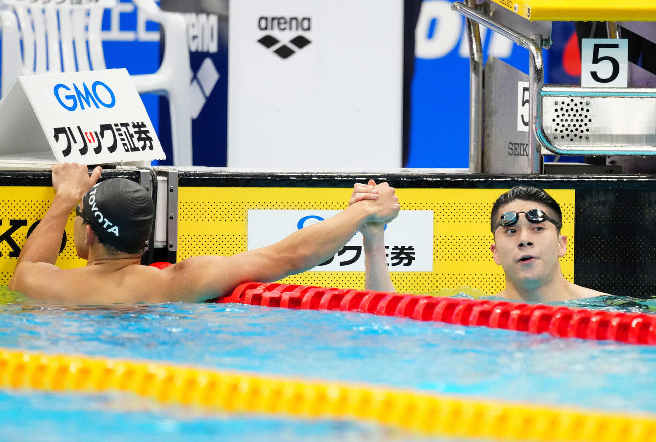 男子100メートルバタフライ決勝で優勝し2位の川本（左）と握手をかわす水沼（撮影・江口和貴）
