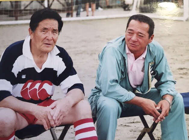 伏見工元監督の山口良治氏（左）とグラウンドで談笑する小畑道弘さん（山口氏提供）
