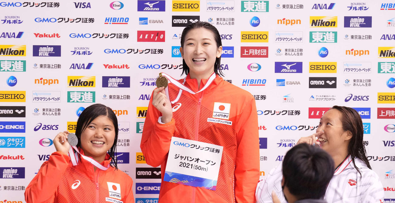 女子100メートルバタフライで優勝の池江（中央）は表彰台で笑顔。左は2位の長谷川、右は3位の相馬（撮影・鈴木みどり）