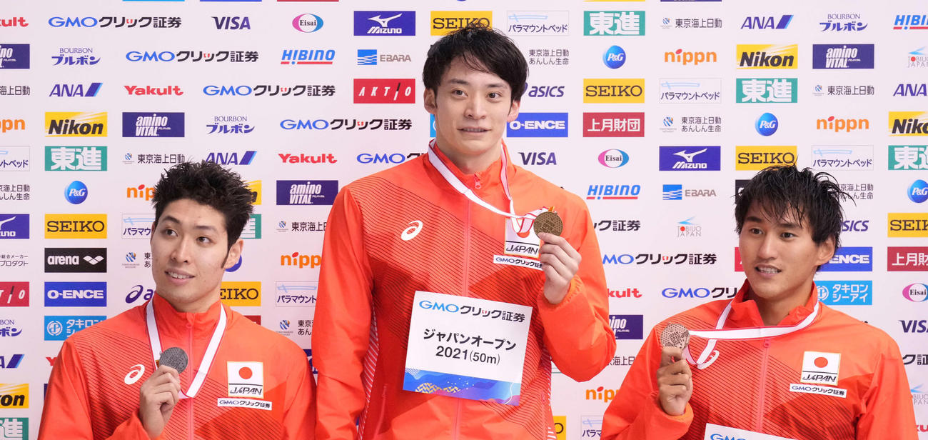 男子200メートル背泳ぎで優勝し表彰台でメダルを手にする入江（中央）。左は2位萩野、右は3位砂間（撮影・鈴木みどり）