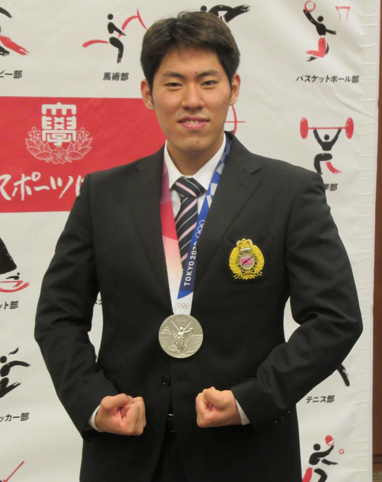 競泳男子の本多灯は、東京五輪の銀メダルを日大に報告し、マッスルポーズ（撮影・益田一弘）