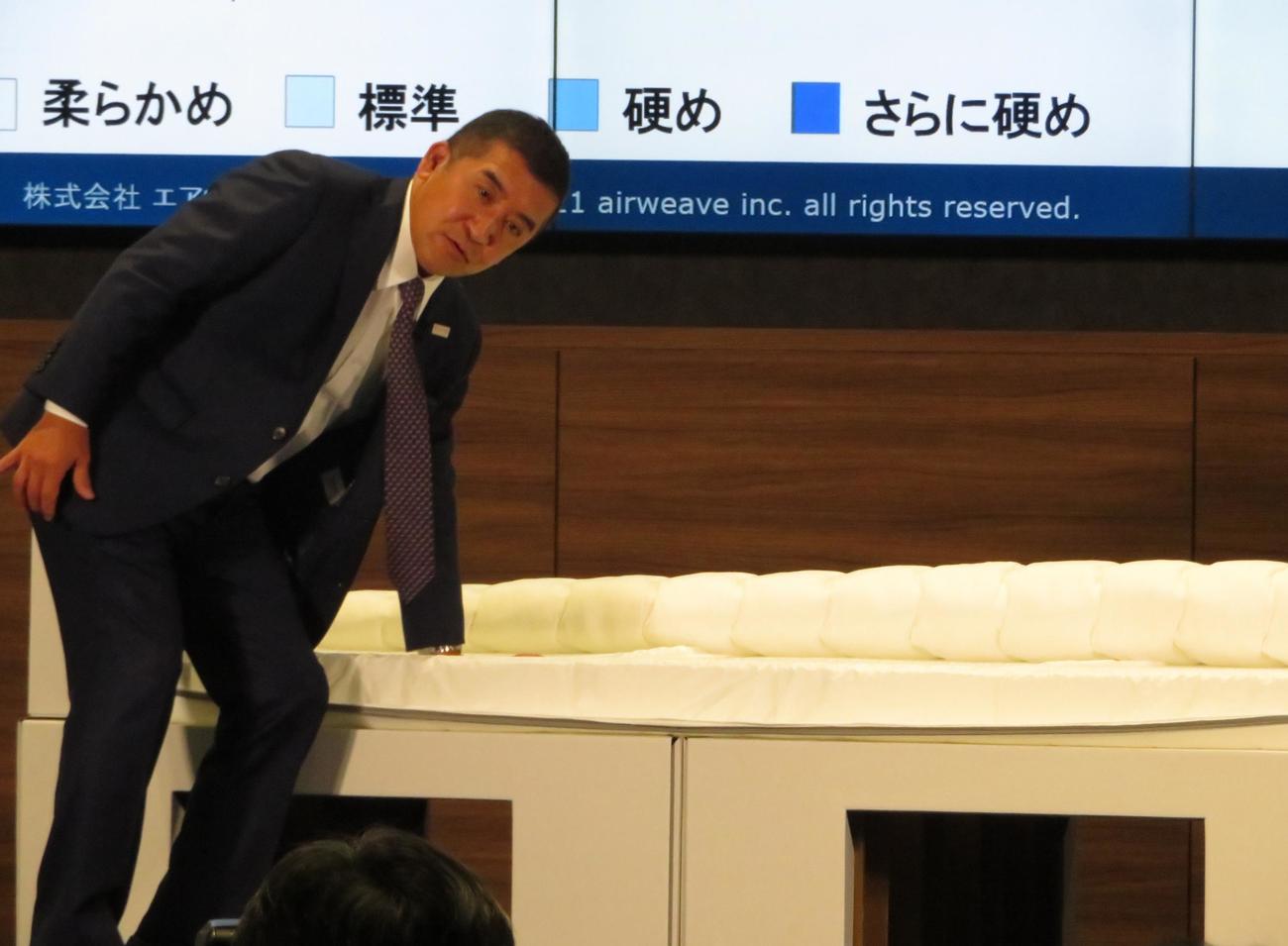 イベントで段ボールベッドの強度を説明する高岡本州会長（撮影・峯岸佑樹）
