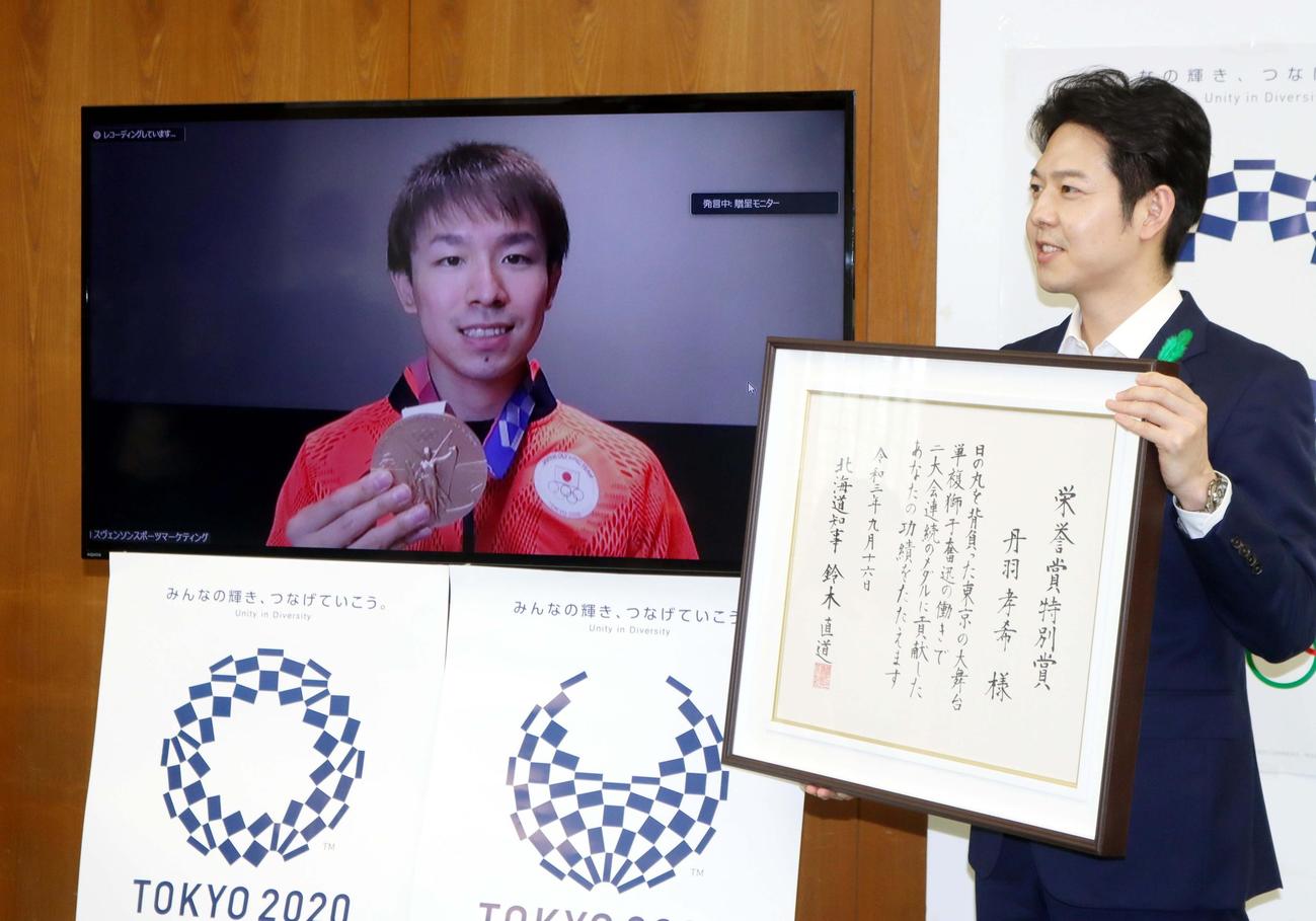 リモートでの表彰式に臨み笑顔の丹羽（左）。右は鈴木知事（撮影・永野高輔）