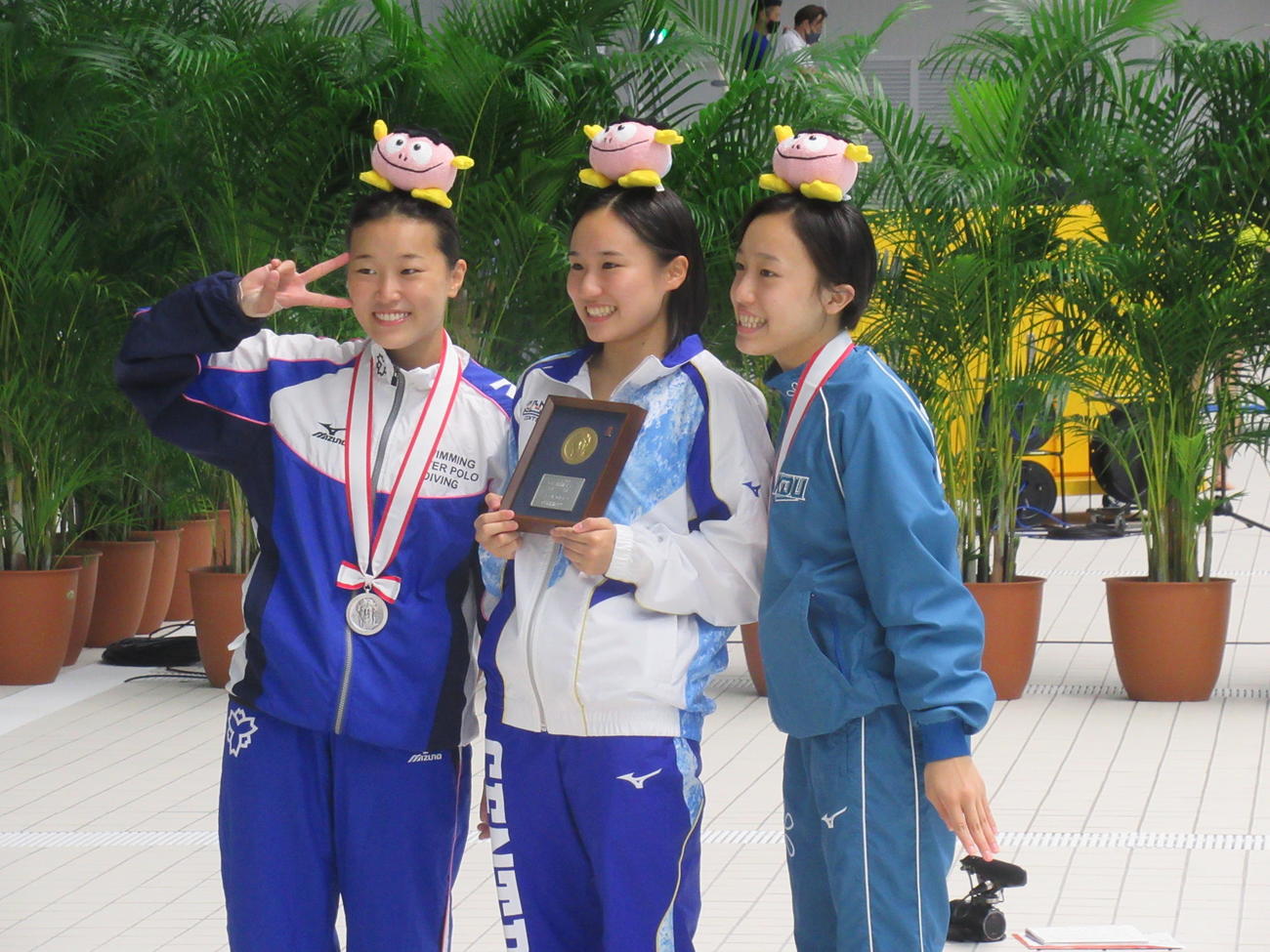 女子3メートル板飛び込みで初優勝した金戸凜（中）。右は3位宮本葉月、左は2位三上紗也可。頭上は日本水連のキャラクター「ぱちゃぽ」（撮影・益田一弘）