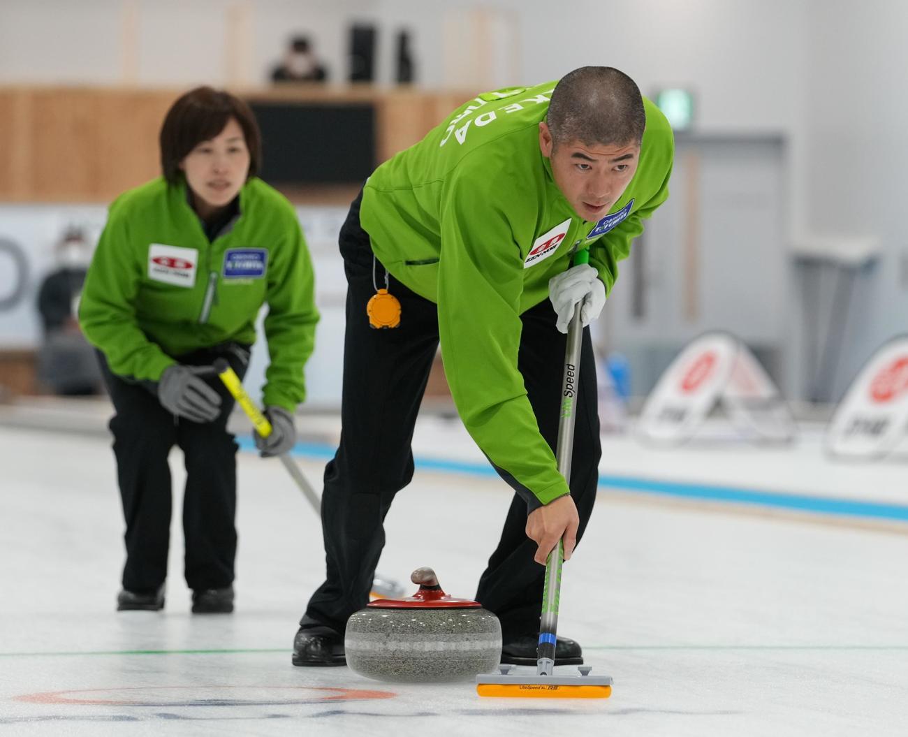 カーリング混合ダブルス日本代表決定戦　第1日　竹田智子、竹田直将組対松村千秋、谷田康真組　第3エンド、スイープする竹田直将。奥は竹田智子（代表撮影）