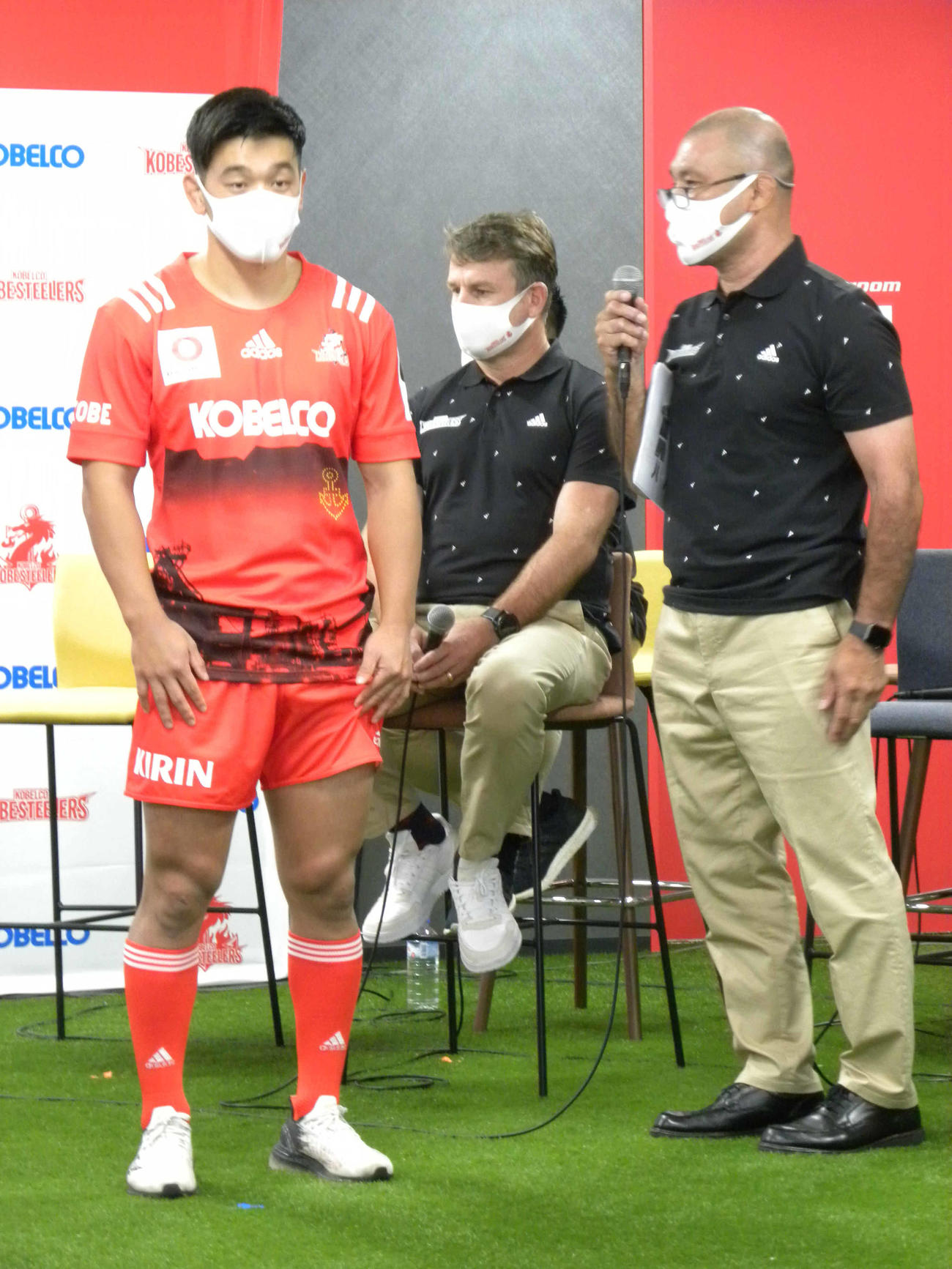 コベルコ神戸スティーラーズの新ジャージーを着たSO李承信（左）と説明する福本正幸チームディレクター（右）（撮影・松本航）