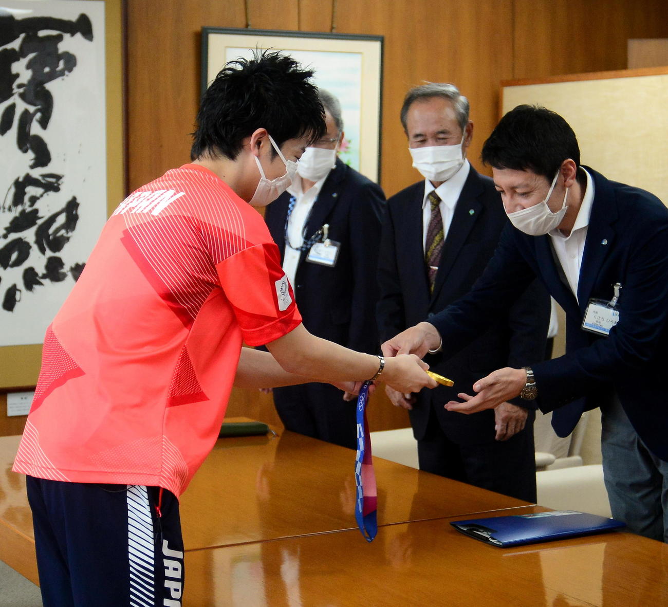 草地市長（手前右）ら関係者にメダルを披露する水谷（同左）