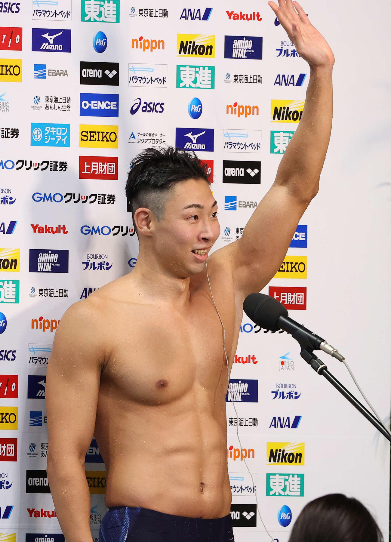 男子50メートル自由形で優勝した川根はインタビュー中、応援席に手を振る（撮影・河野匠）