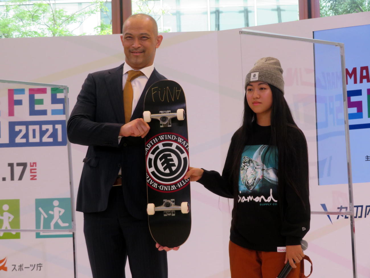 スケートボードの中山楓奈からサイン入りボードをプレゼントされ笑顔のスポーツ庁室伏広治長官（左）（撮影・三須一紀）