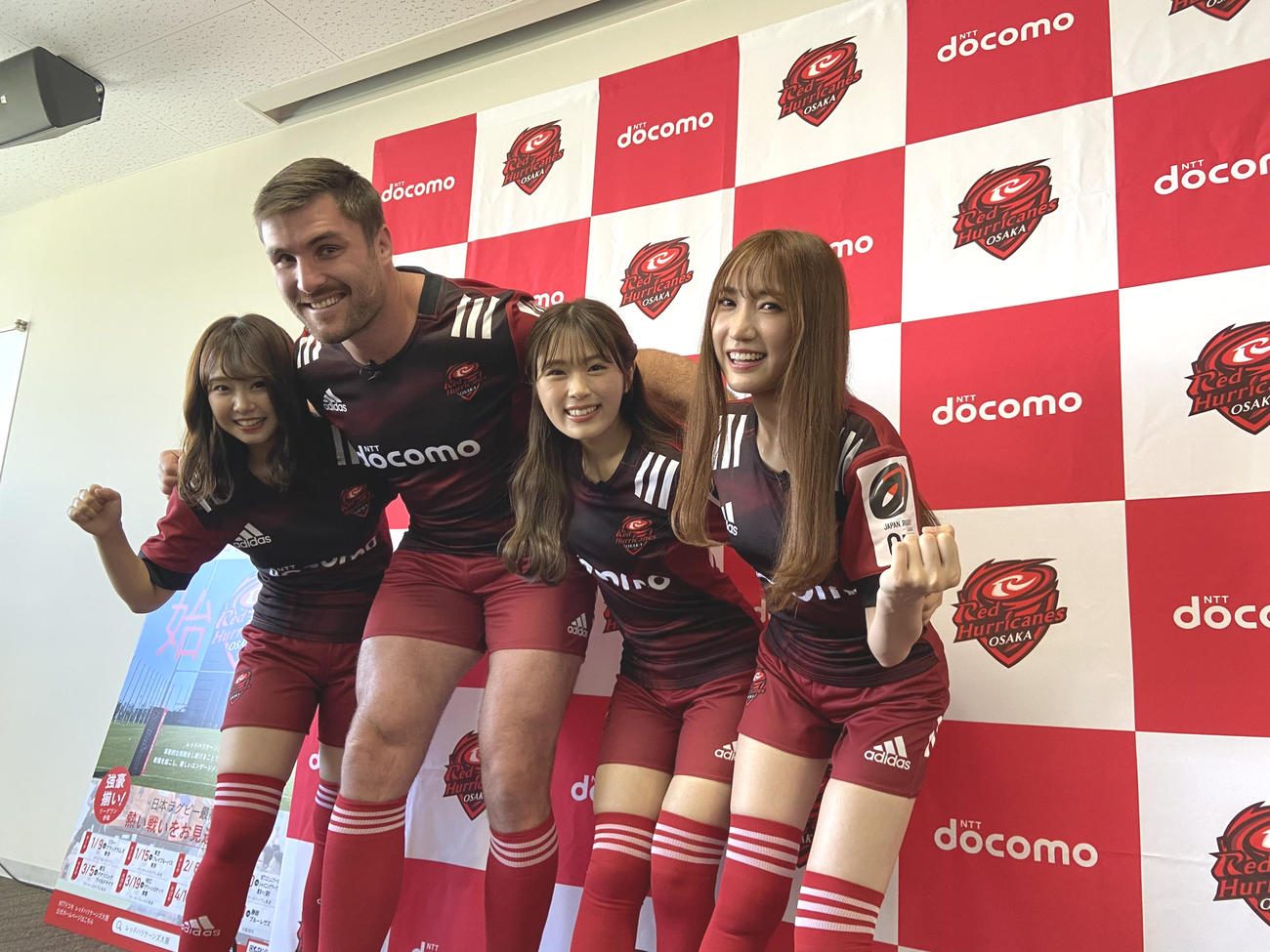 NTTドコモレッドハリケーンズ大阪の公式アンバサダーに就任したNMB48の加藤夕夏（左端）、渋谷凪咲（右から2人目）、原かれん（右端）はエラスマス主将とスクラムを組む（撮影・松本航）
