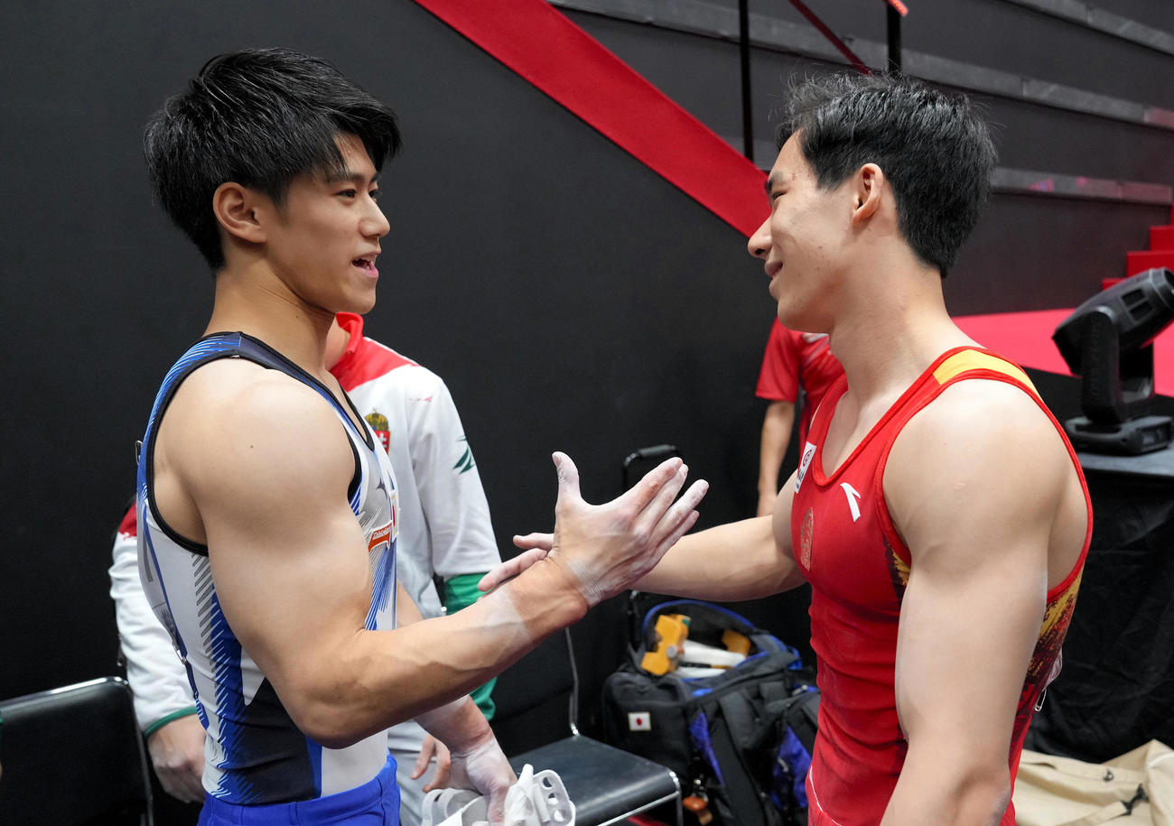 男子個人総合決勝の演技終了後、握手を交わす橋本大輝（左）と中国の張博恒（代表撮影）
