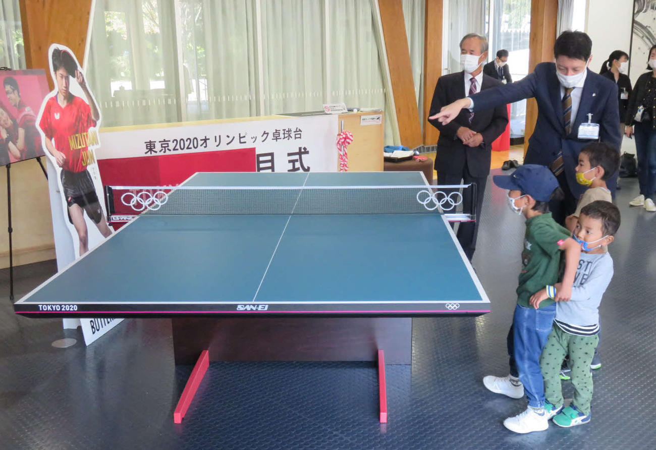 東京五輪で使用された卓球台について、子どもたちに説明する草地市長（右奥）