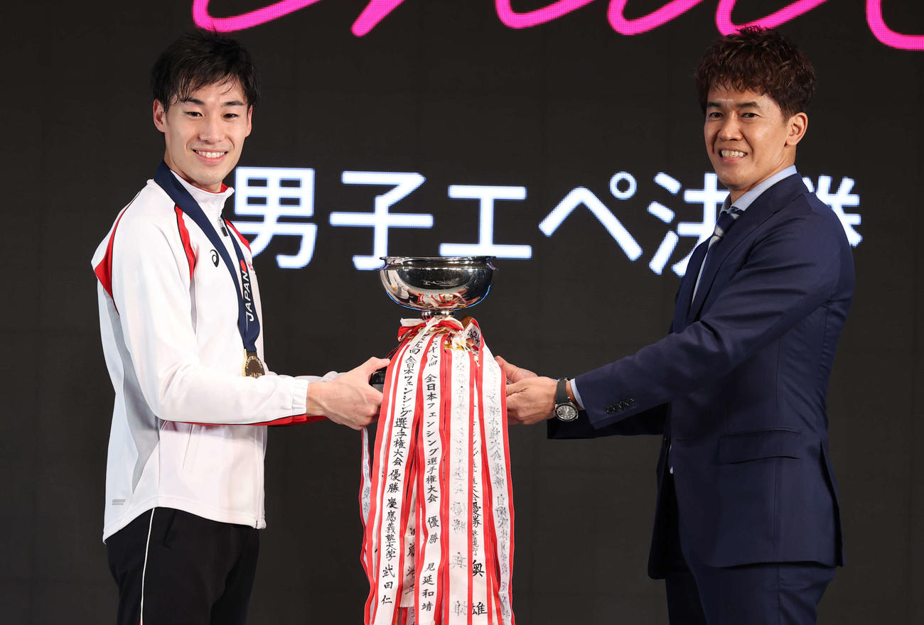 男子エペで優勝した加納（左）は武井会長から優勝杯を受け取り笑顔を見せる（撮影・河野匠）