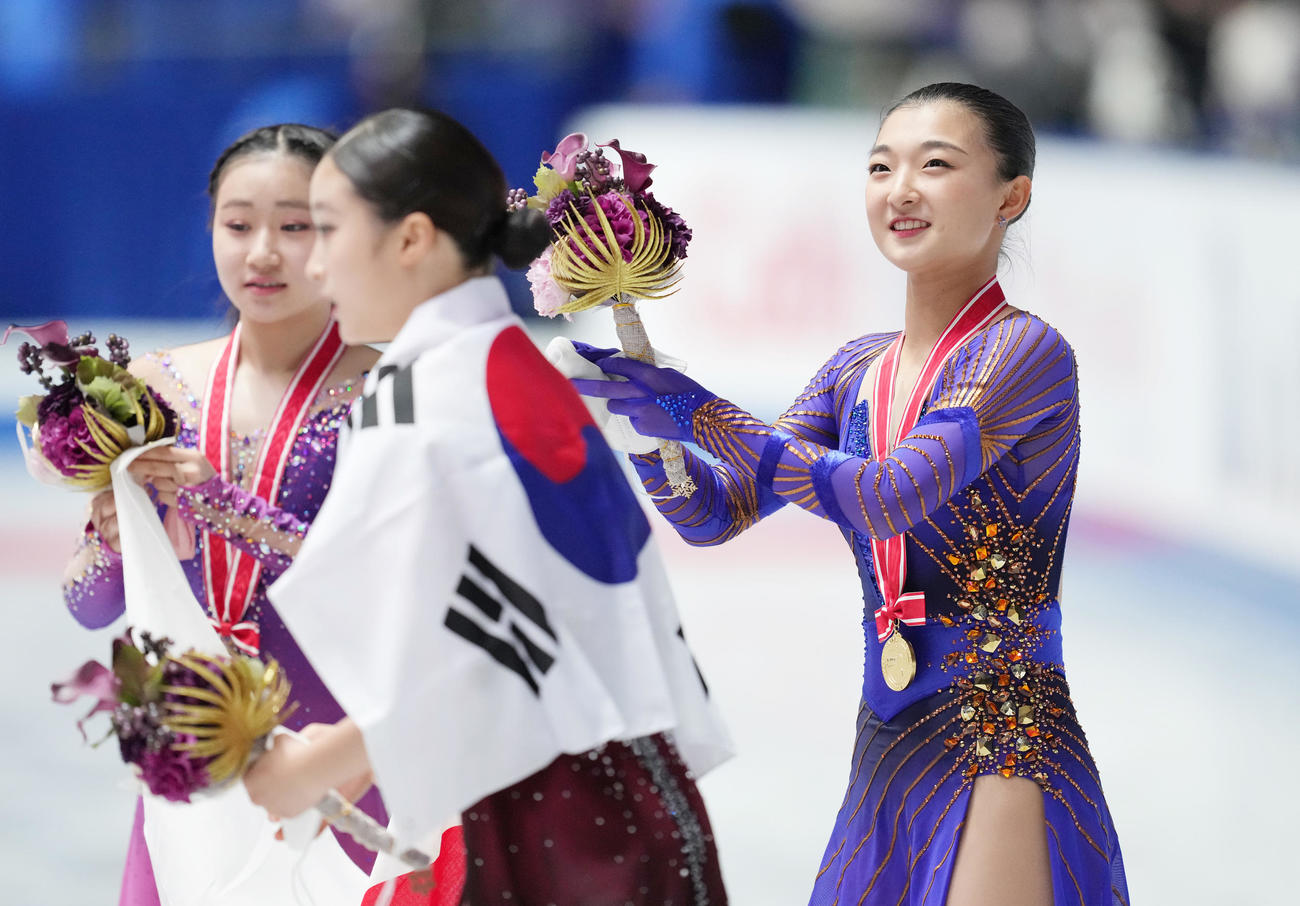 NHK杯女子で優勝し、メダルをかけ笑顔を見せる坂本。左は2位河辺、中央は3位ユ・ヨン（撮影・菅敏）