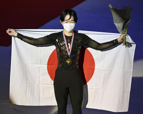 男子で優勝し、メダルを胸に日の丸を掲げる鍵山優真＝グルノーブル（共同）