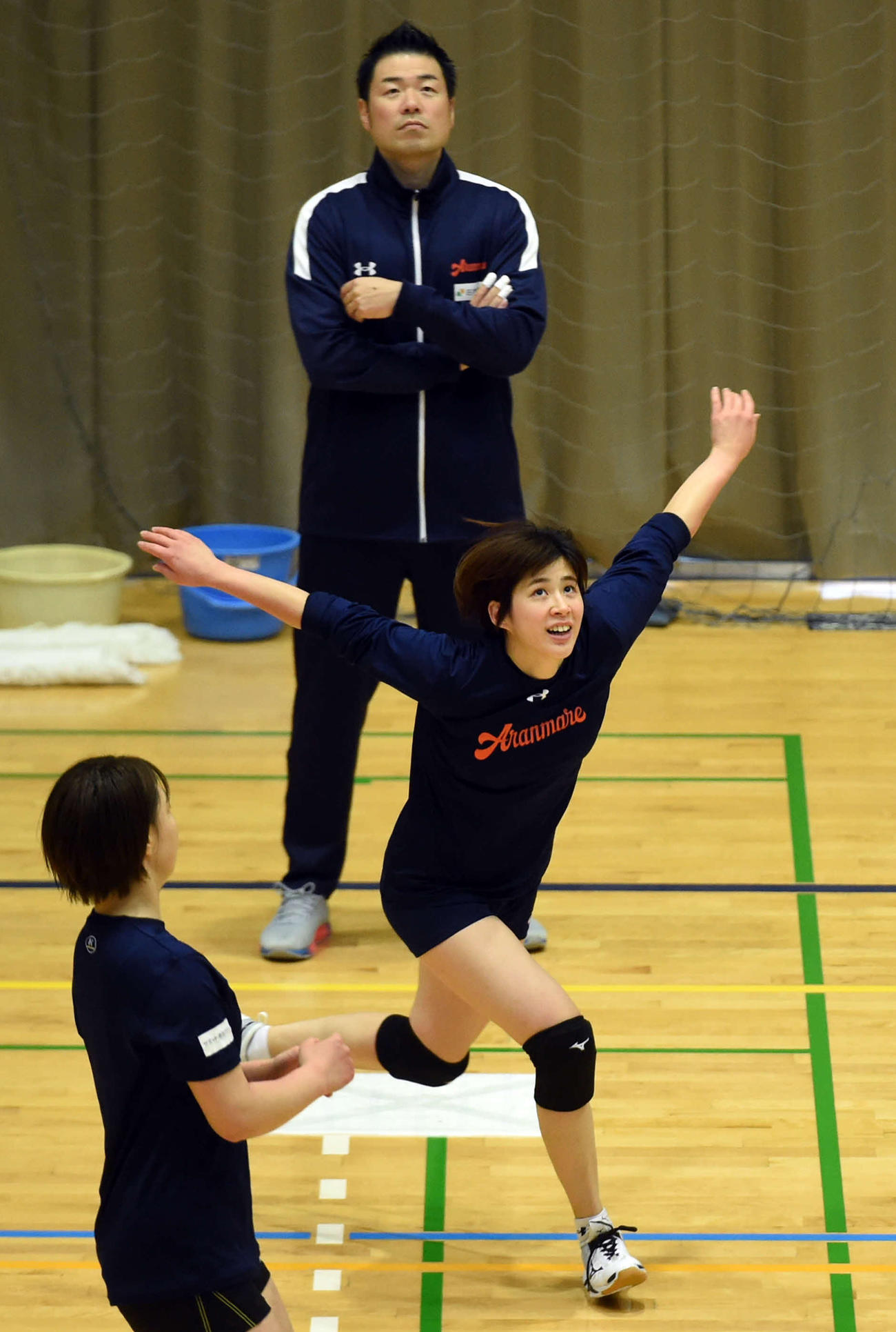 両腕を広げ、スパイクの動作に入る木村（中央）。後方は北原監督