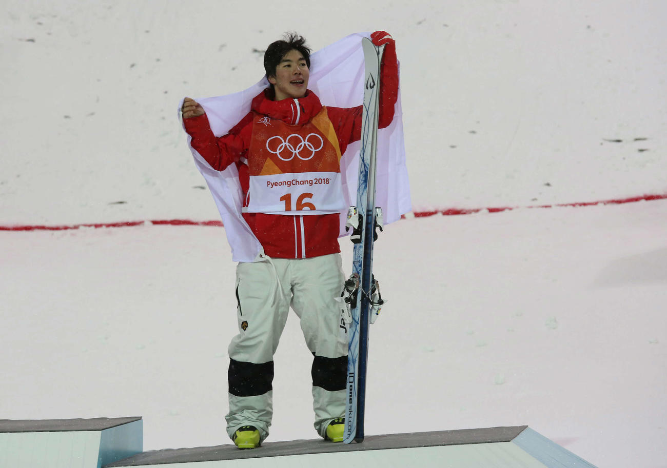 平昌五輪　フリースタイルスキー男子モーグル表彰式　銅メダルを決めた原大智は、日の丸を掲げて笑顔を見せる（2018年2月12日撮影）