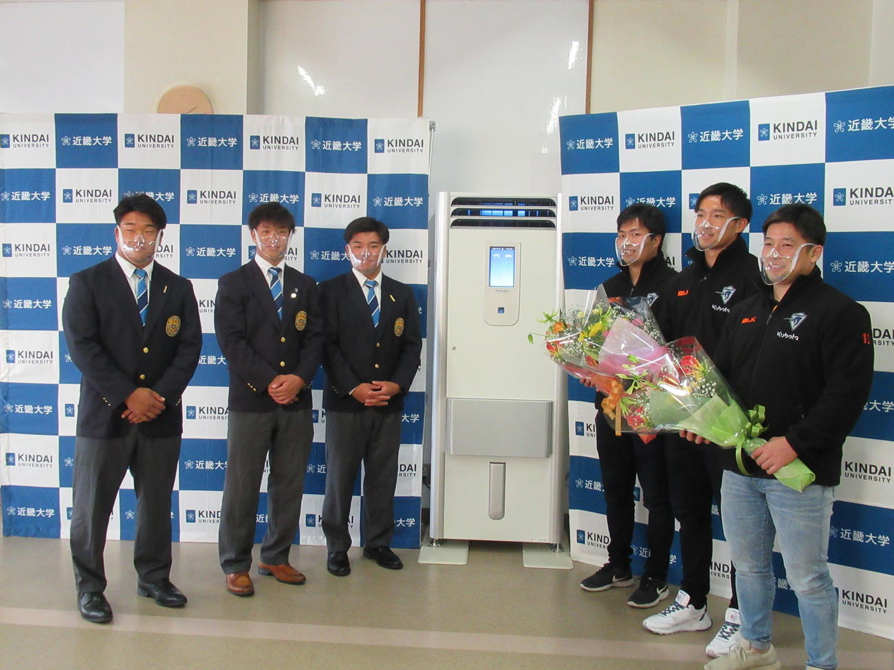 クボタスピアーズ船橋・東京ベイの選手（右3人）から加湿空気清浄機を寄贈される近大プロップ紙森（左）らラグビー部のメンバー