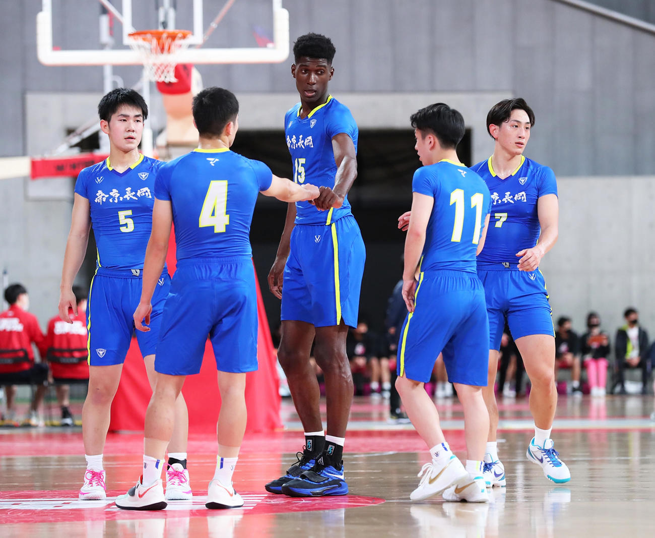 白樺学園対帝京長岡　第2Q、コートでタッチを交わす帝京長岡のニシンバ（中央）ら（C）