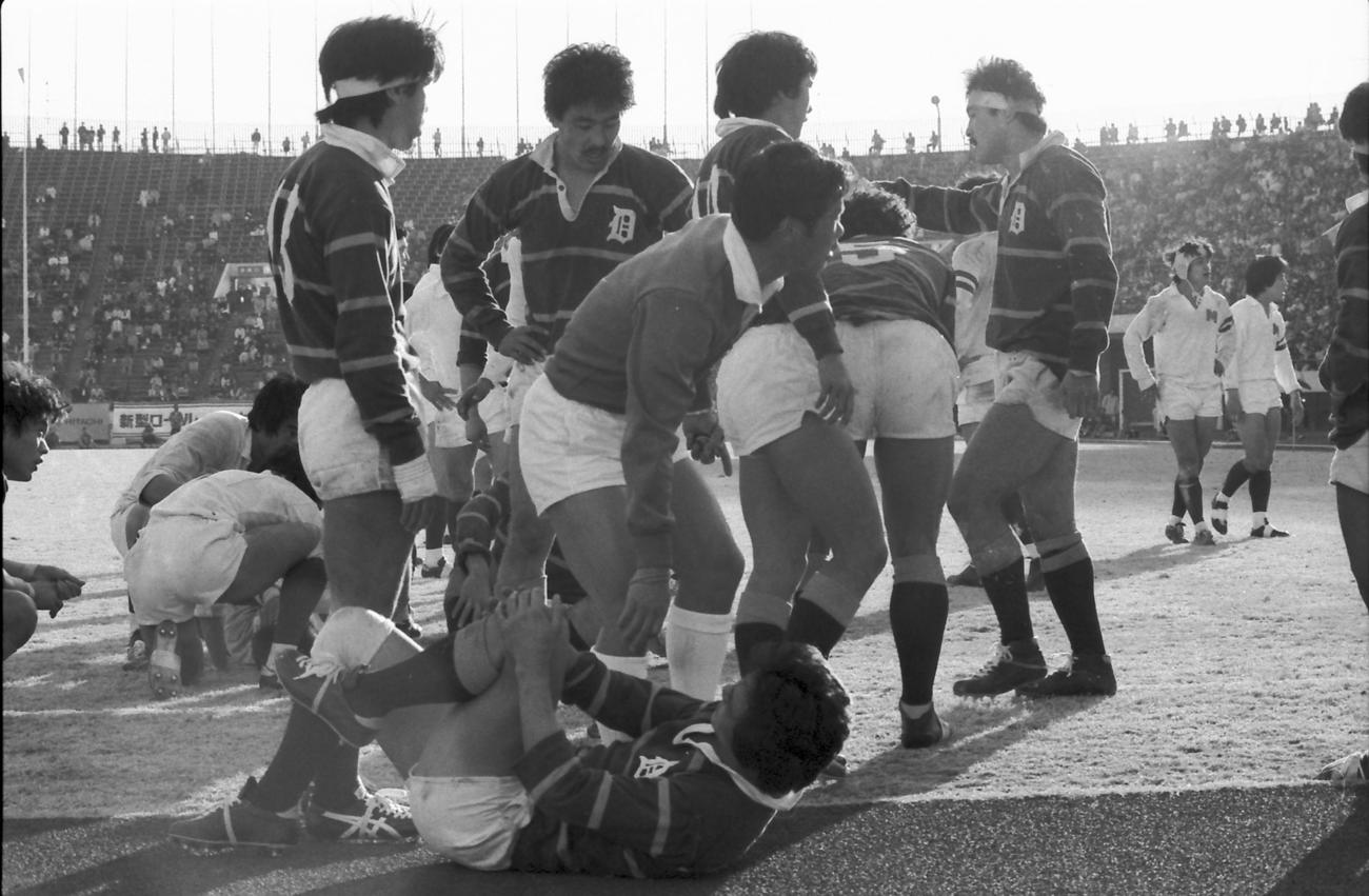 第18回ラグビー大学選手権準決勝　明治大対同志社大　ボールをめぐり、両チームの選手がラックに突っ込み、試合が一時中断する。中央は大島真也に退場を宣告した高森レフェリー（1982年1月2日撮影）