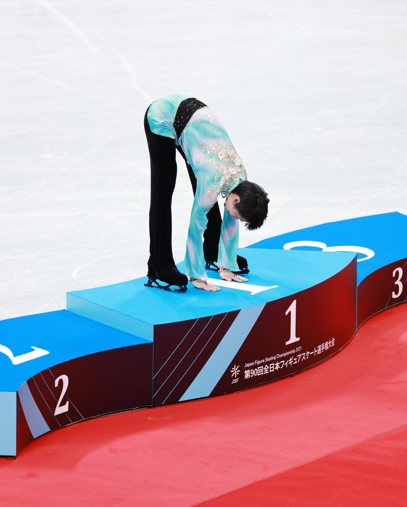 男子を制した羽生は表彰台の「1」の文字をなでる羽生（撮影・垰建太）